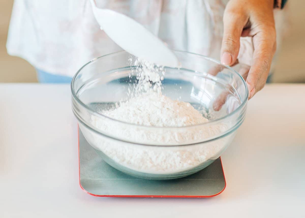 a women measuring flour with a kitchen scale.