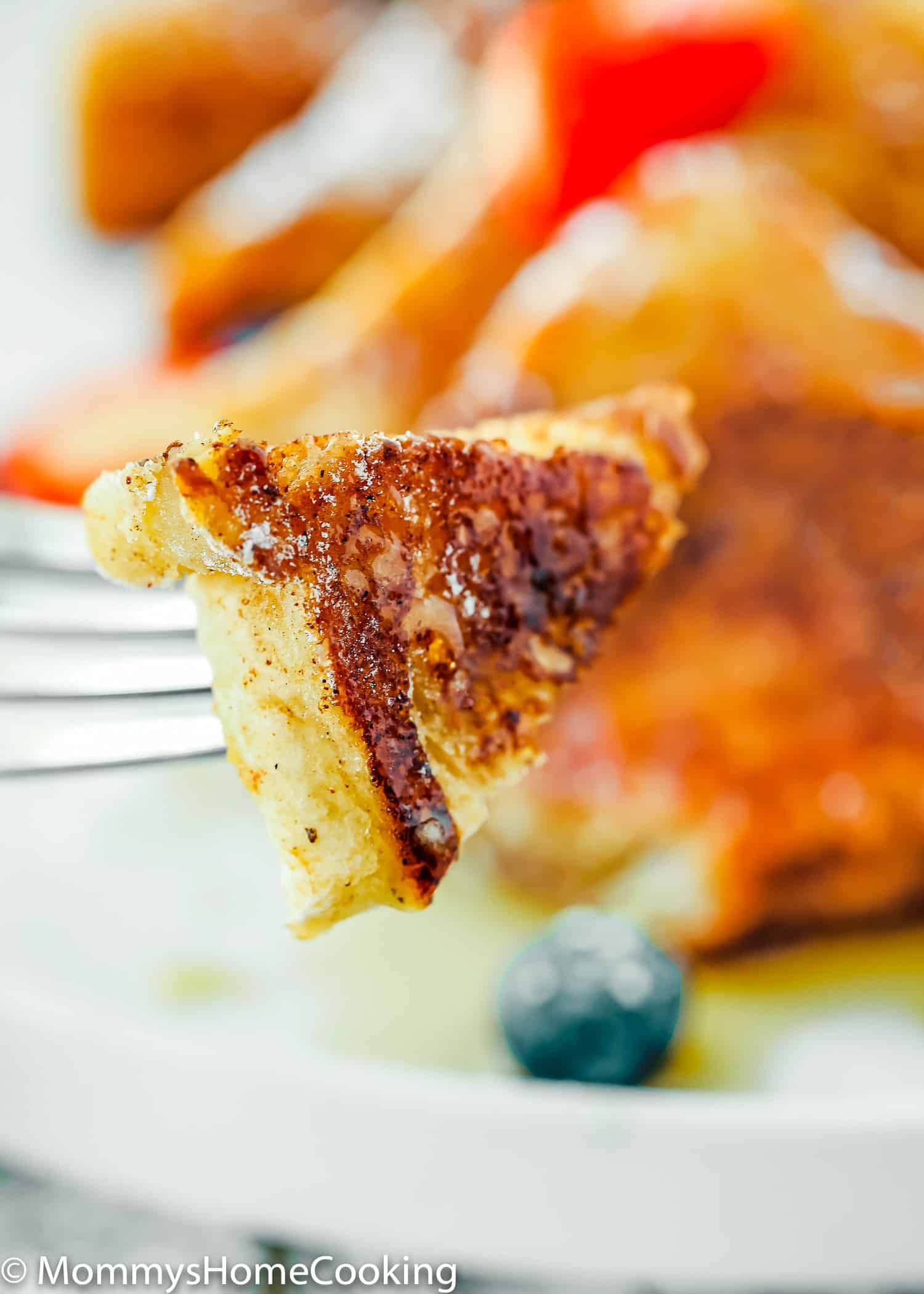 A fork with a bite-sized piece of French toast on it.