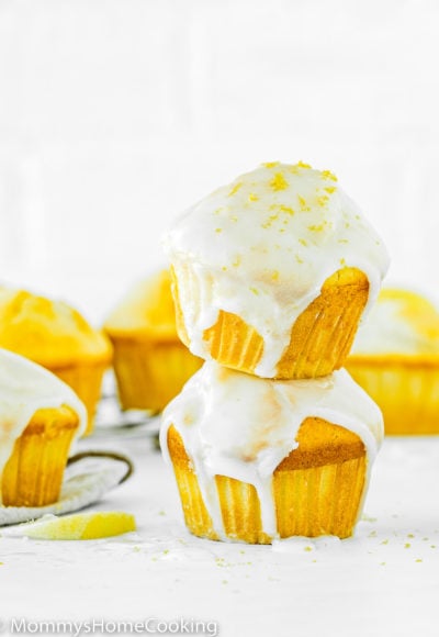 a stack of two Eggless Lemon Muffins with glaze, with more egg-free Muffins around it.