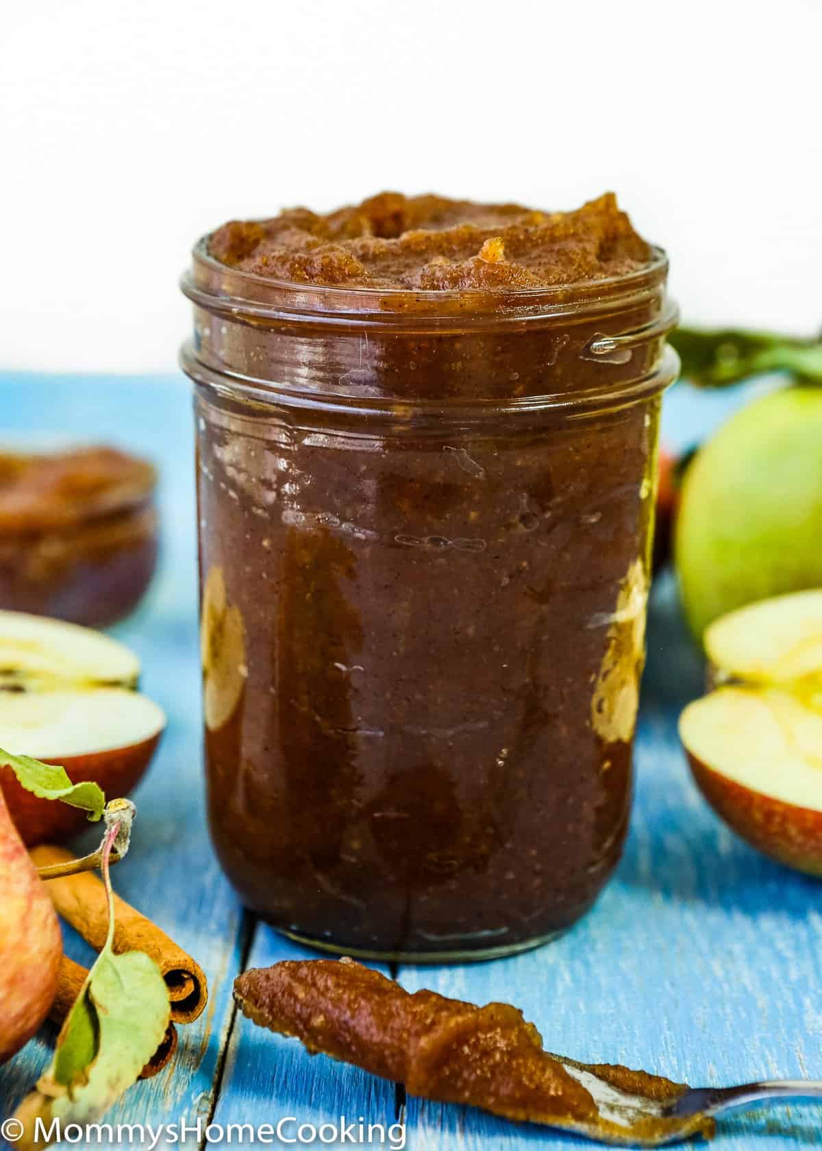 apple butter in a jar jar with fresh apples around it