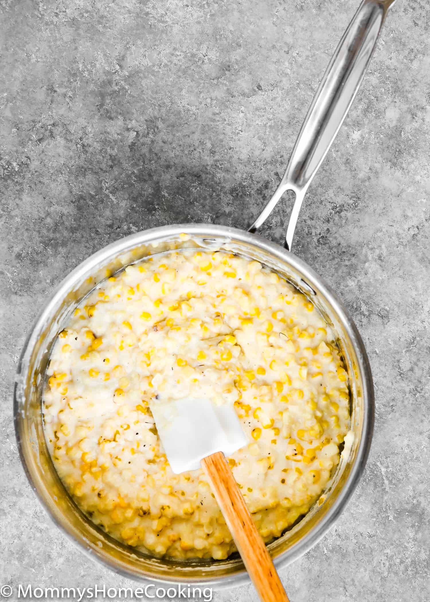 eggless corn fritter mixture in a sauce pan with a spatula. 