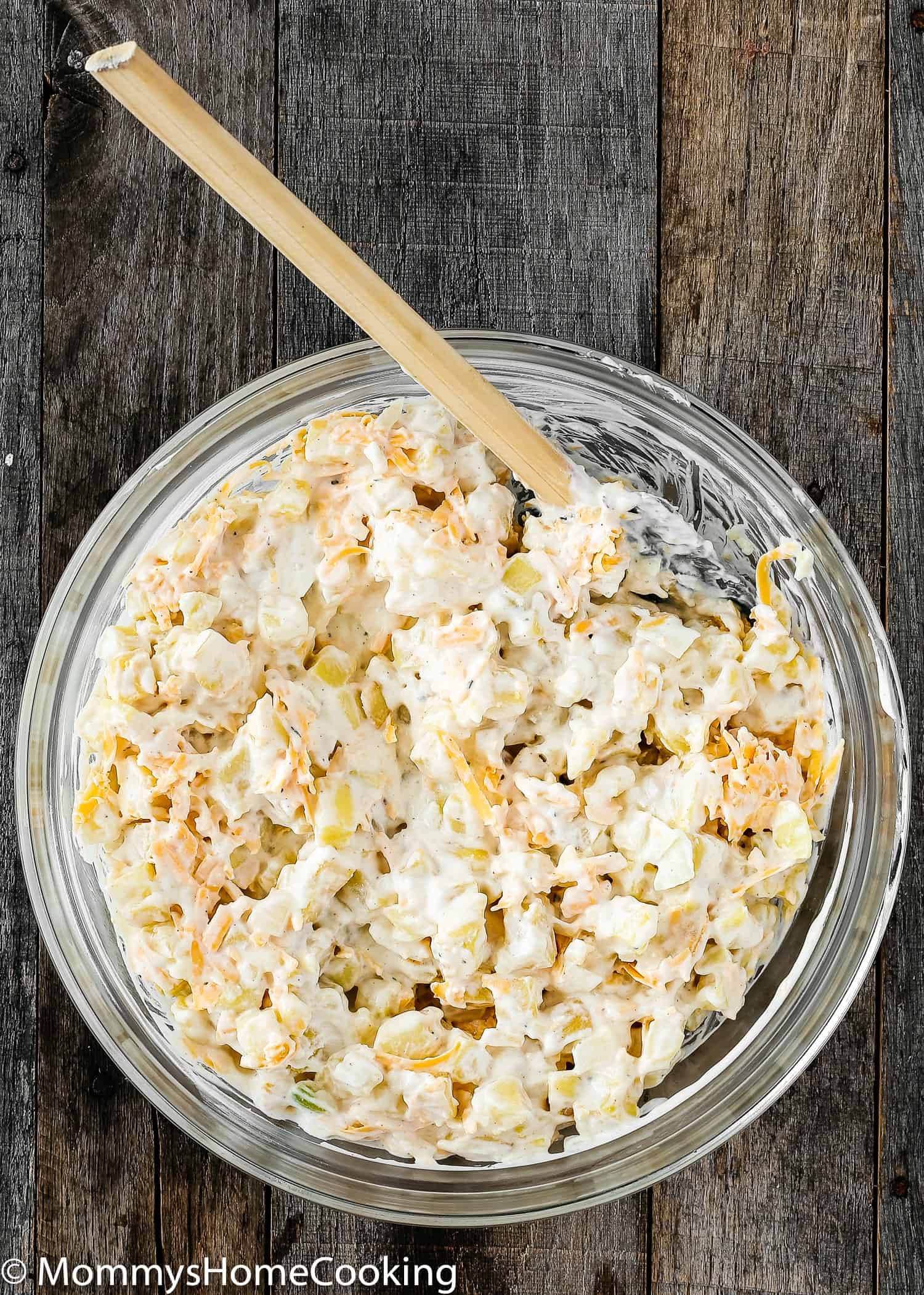 ingredients to make potato casserole in a bowl with a spatula.