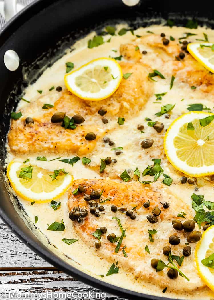 creamy chicken piccata in a skillet with lemon slices