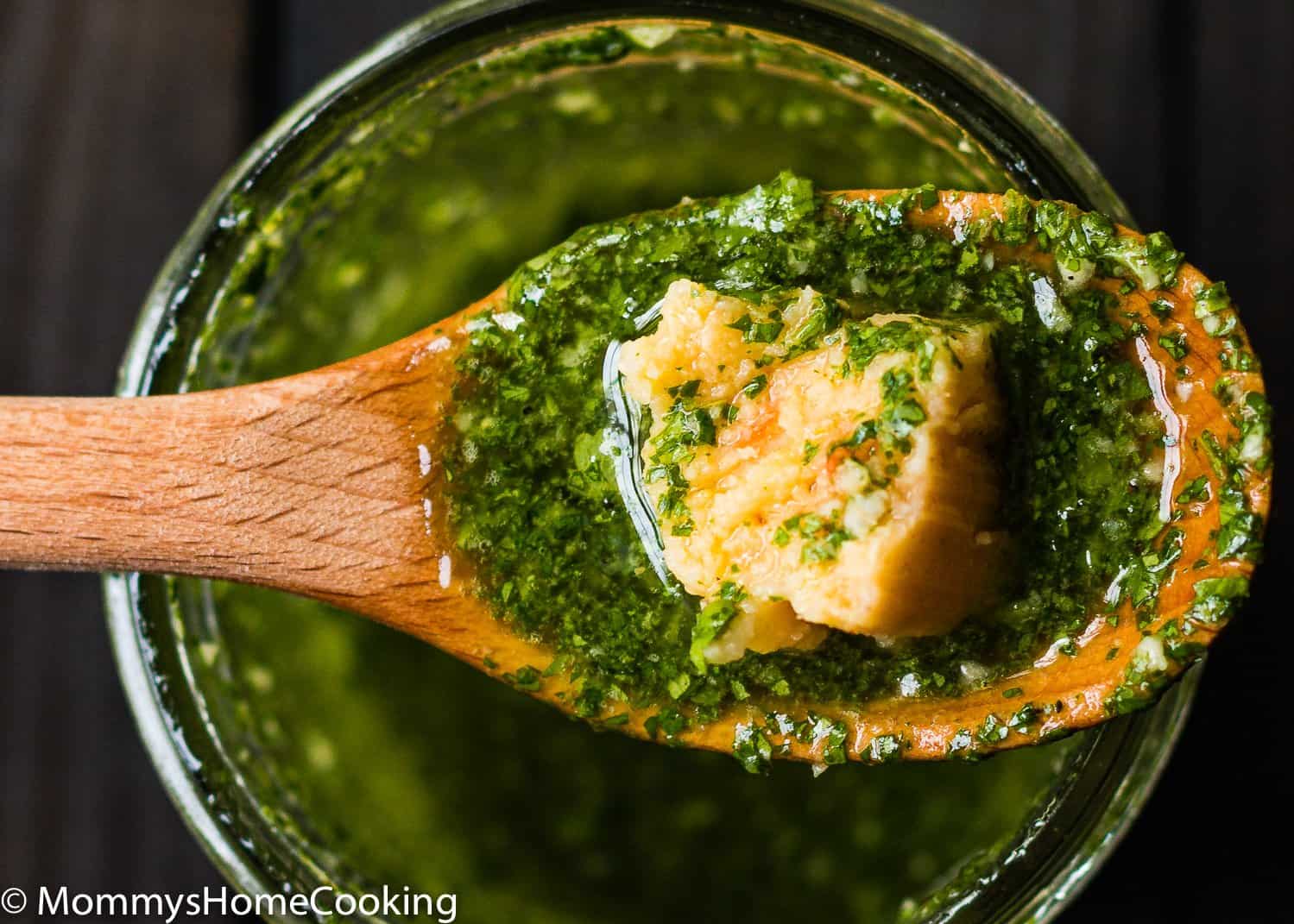 a wooden spoon with cilantro mojo and a piece of venezuelan hallaquita.