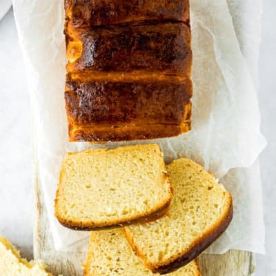 overhead view of a loaf of eggless brioche bread sliced over a wooden board