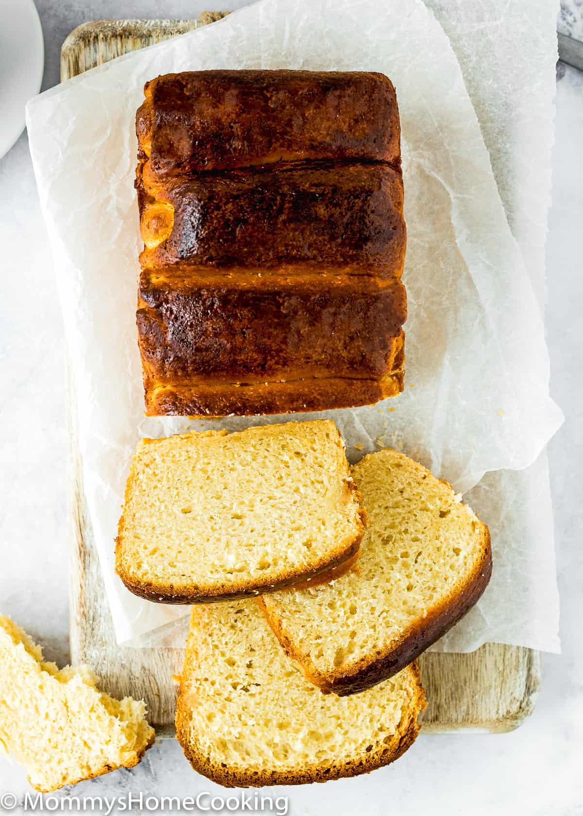 overhead view of a loaf of eggless brioche bread sliced over a wooden board.