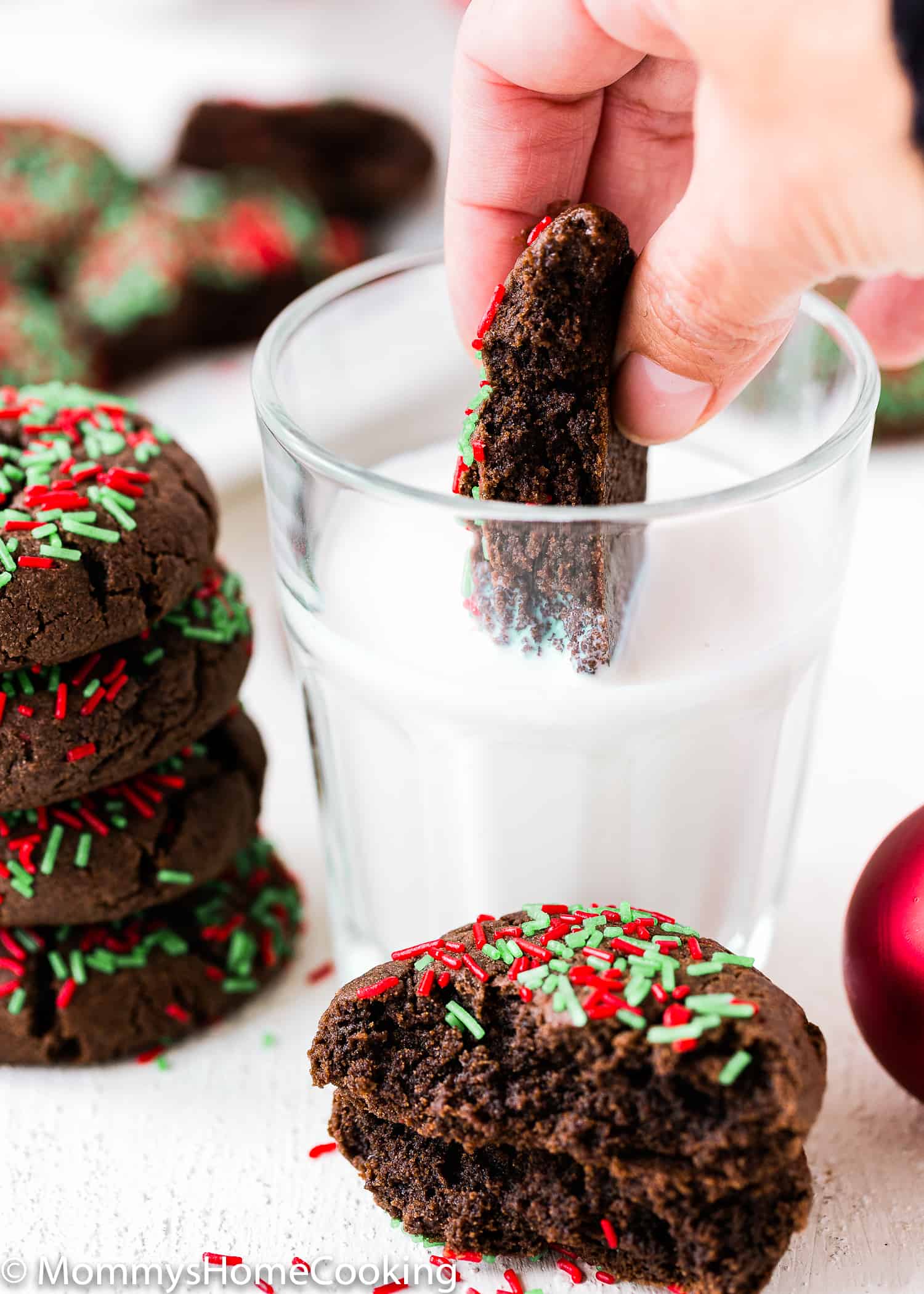 a hand dipping a  Easy Eggless Cake Mix Christmas Cookie into a glass of milk