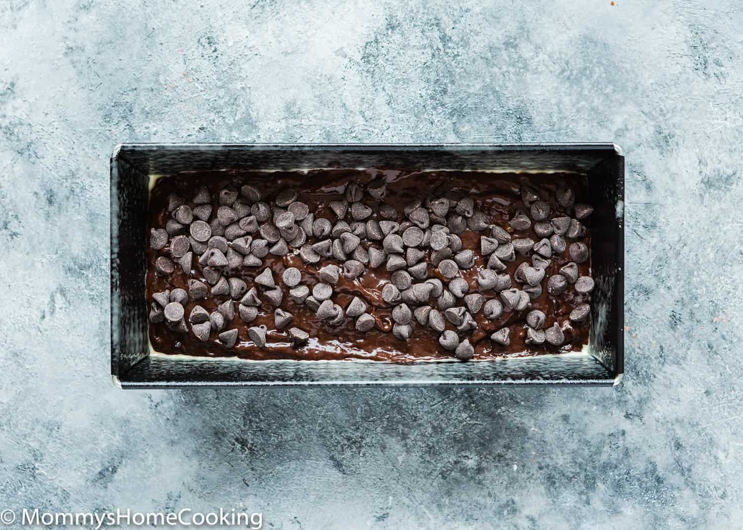Eggless Chocolate Banana Bread batter in a loaf pan with chocolate chip on top.