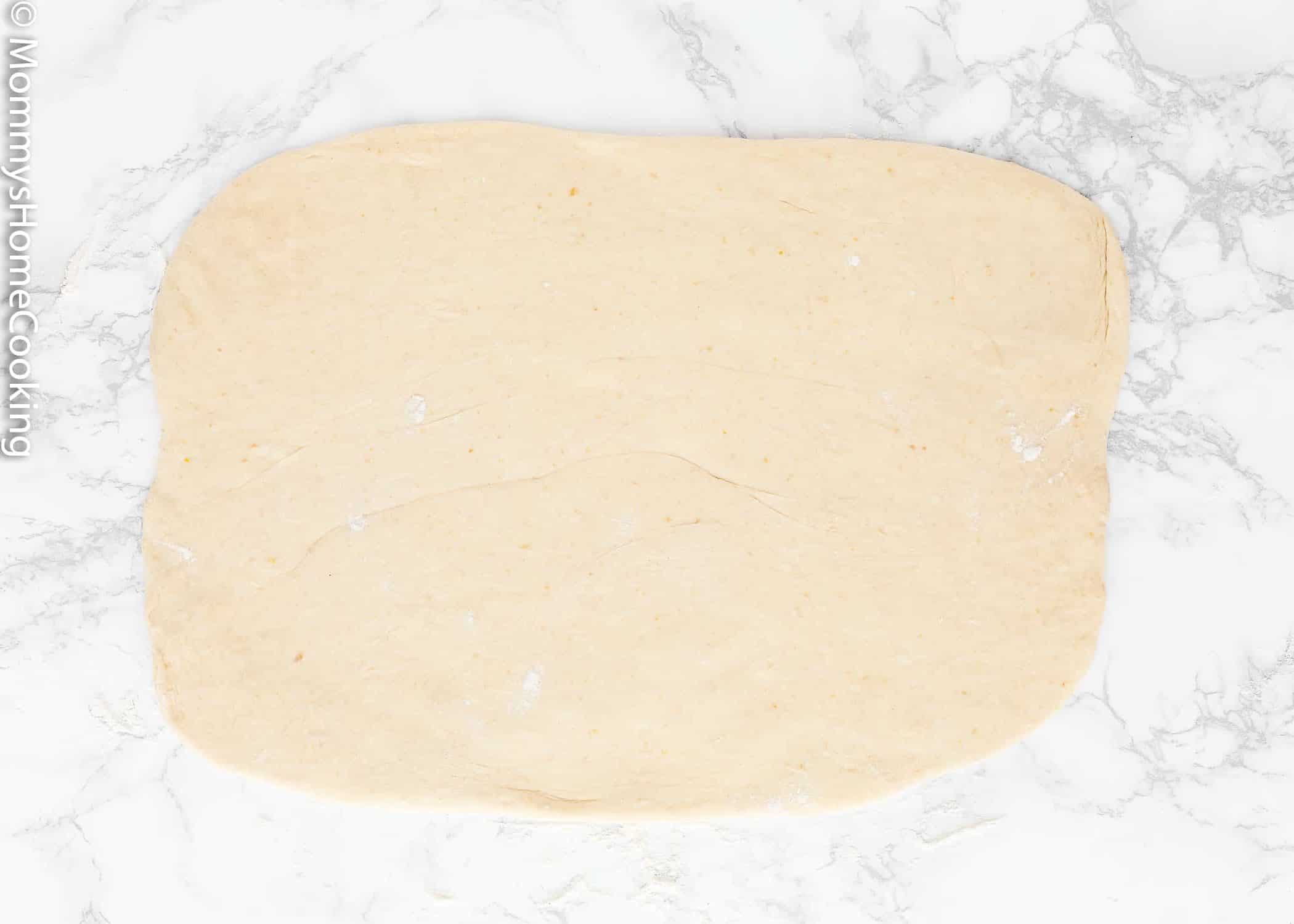 Egg-free cinnamon roll dough rolled out into a rectangle. 
