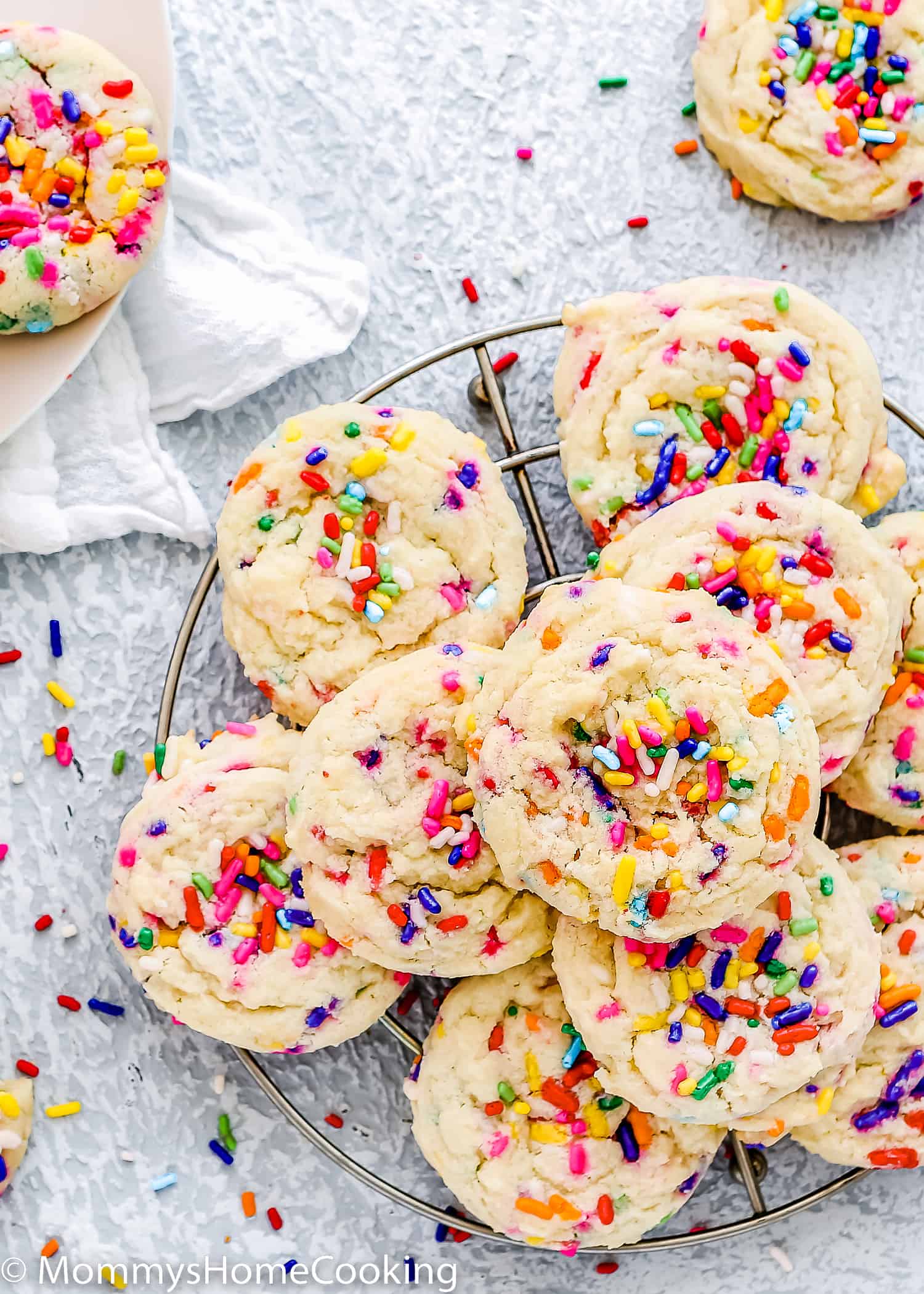eggless confetti cookies on a cooling rack over a blue surface.