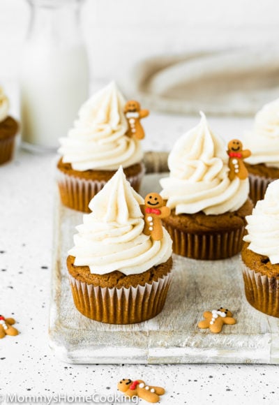 Eggless Gingerbread Cupcakes with cinnamon cream cheese frosting over a wooden surface with a bottle of milk in the background