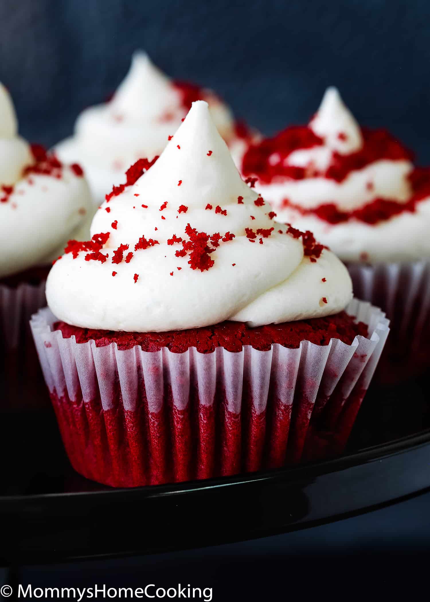 Egg-free red velvet cupcake with frosting and red velvet crumble on top.