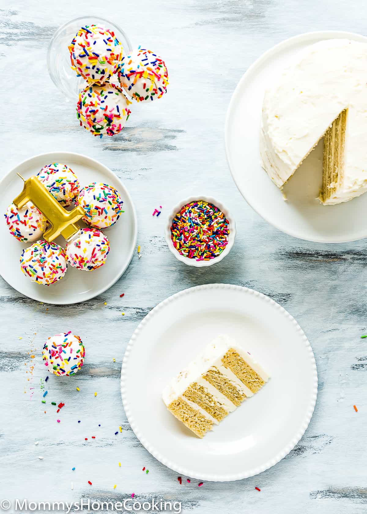 overhead view eggless smash cake sliced with cake pops and a candle on a blue surface