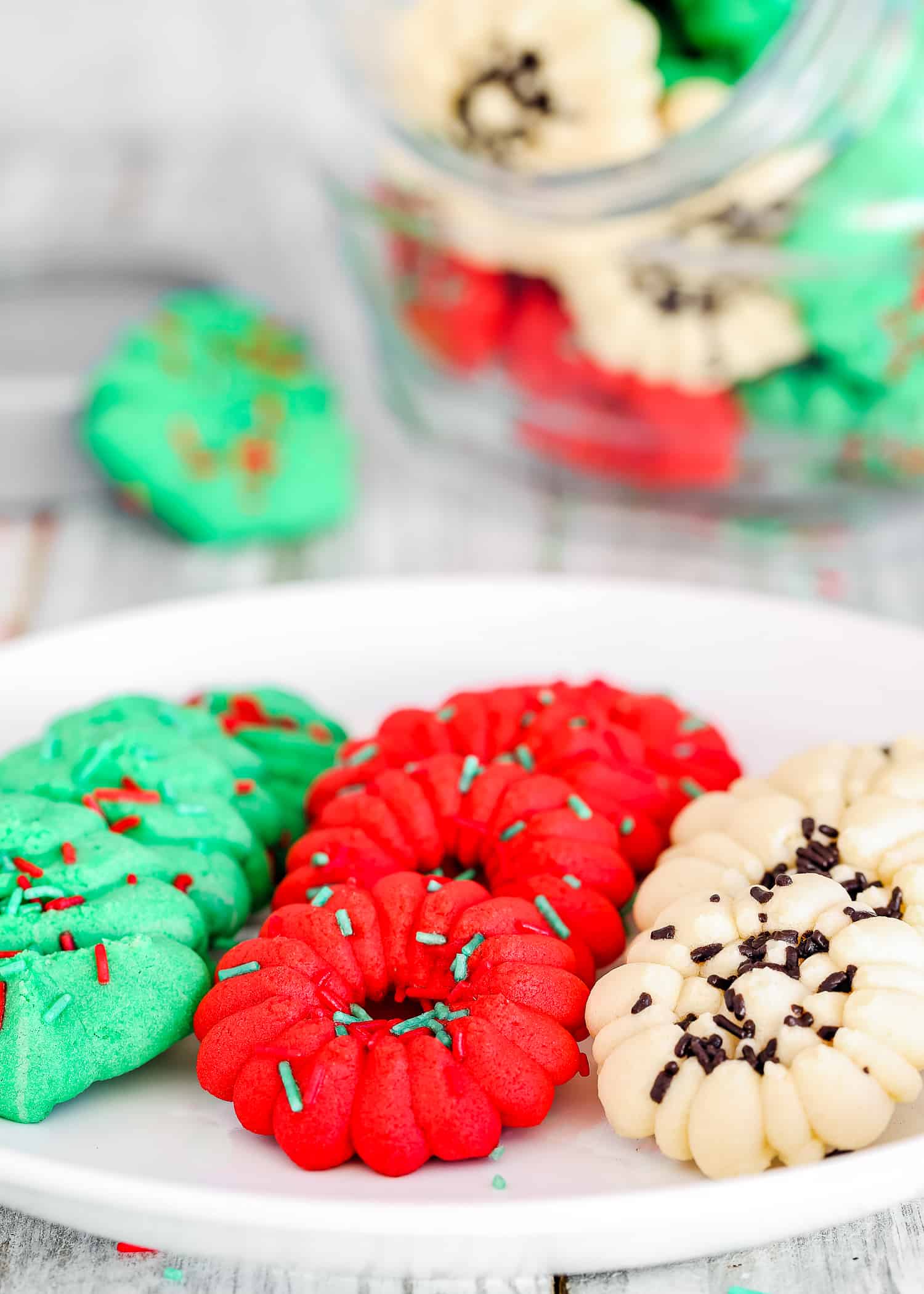 Eggless Spritz Cookies on a plate with sprinkle ons top. 