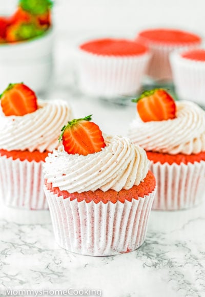eggless Strawberry cupcakes with strawberry buttercream and fresh Strawberry on top over a marble surface.
