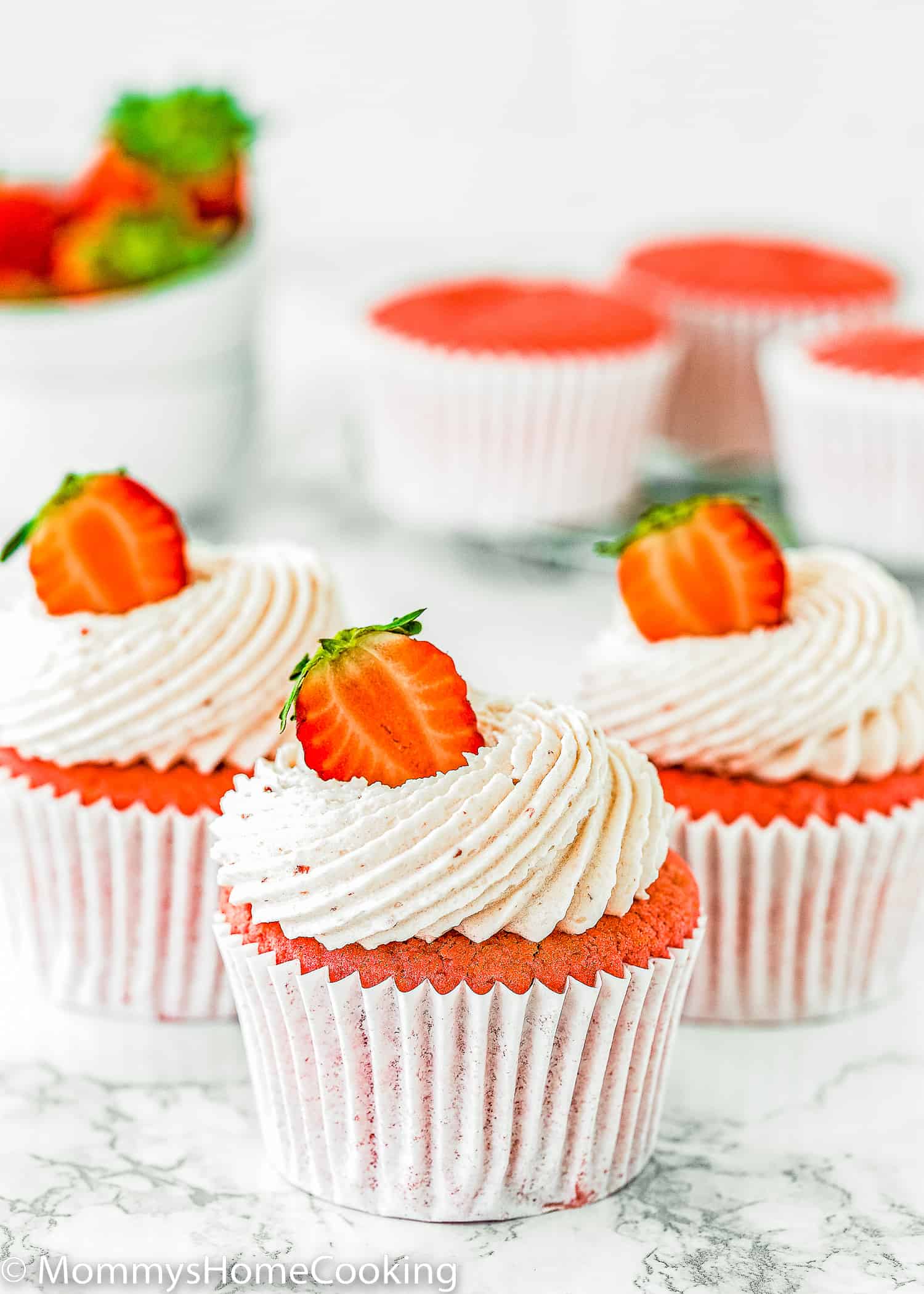 three eggless Strawberry cupcakes with strawberry buttercream and fresh Strawberry on top.