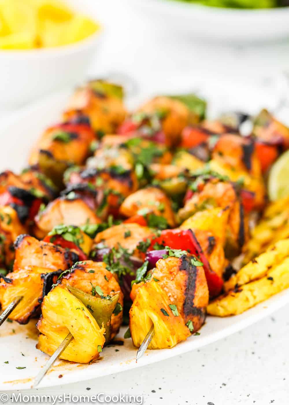 Easy Grilled Hawaiian Chicken Skewers in a white plate with lemon wedges and grilled pineapple close up