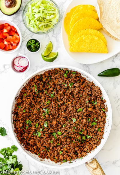 Cooked Ground Beef for Tacos in a skillet surrounded by taco toppings.