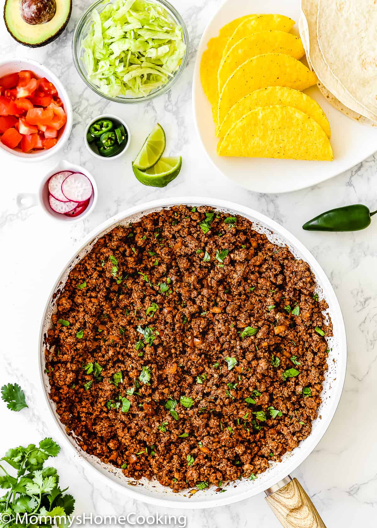 Cooked Ground Beef for Tacos in a skillet  surrounded by taco toppings.