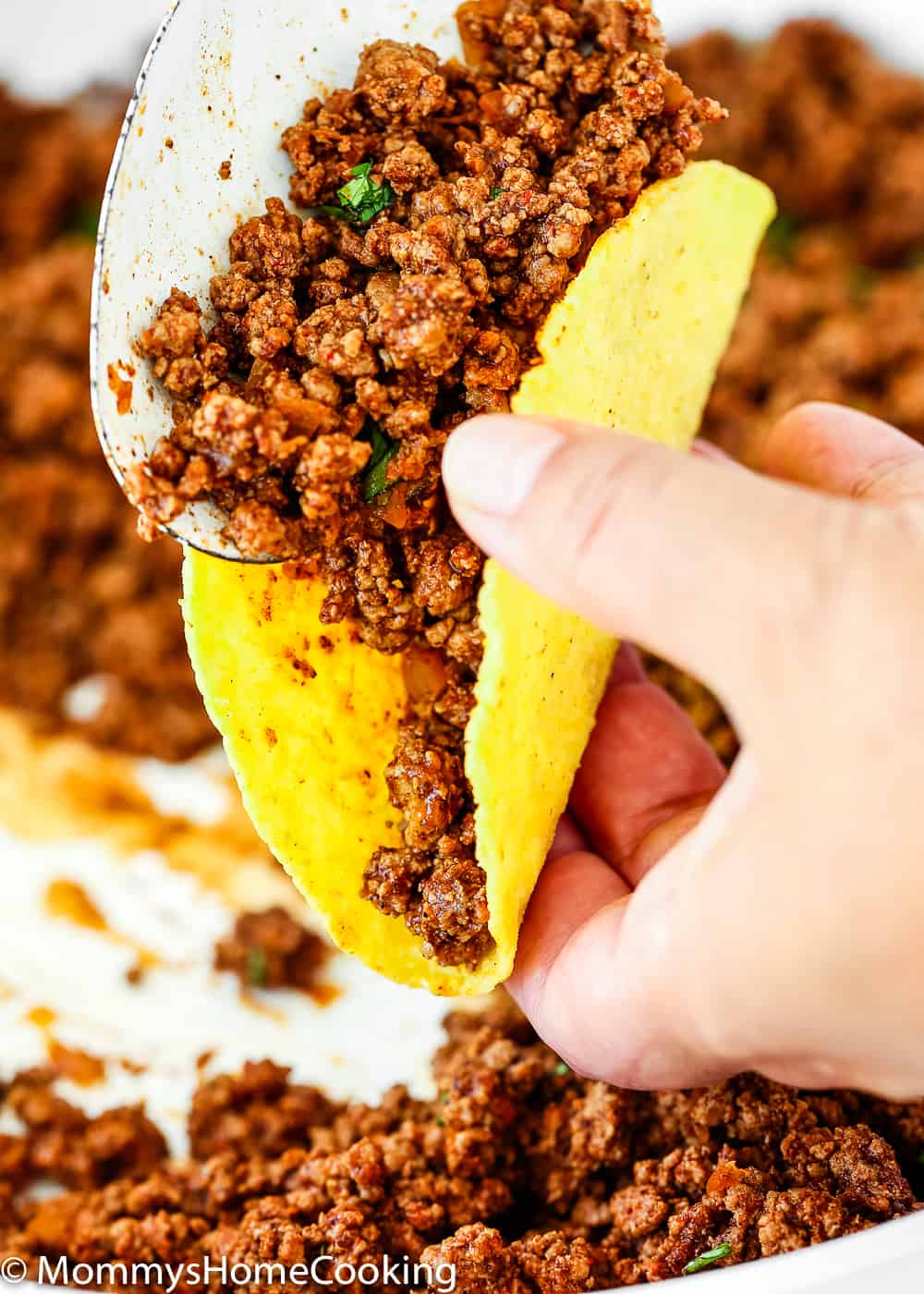 Serving taco ground beef into a taco shell.