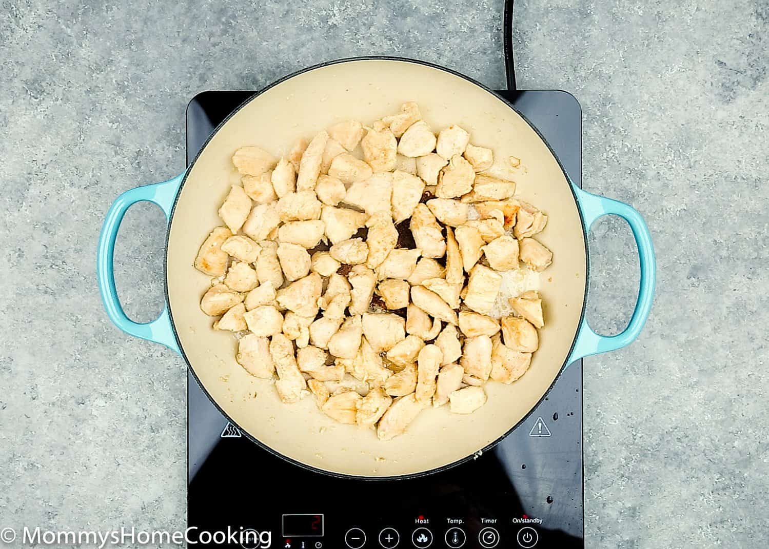 chicken breast being cooked in a blue skillet