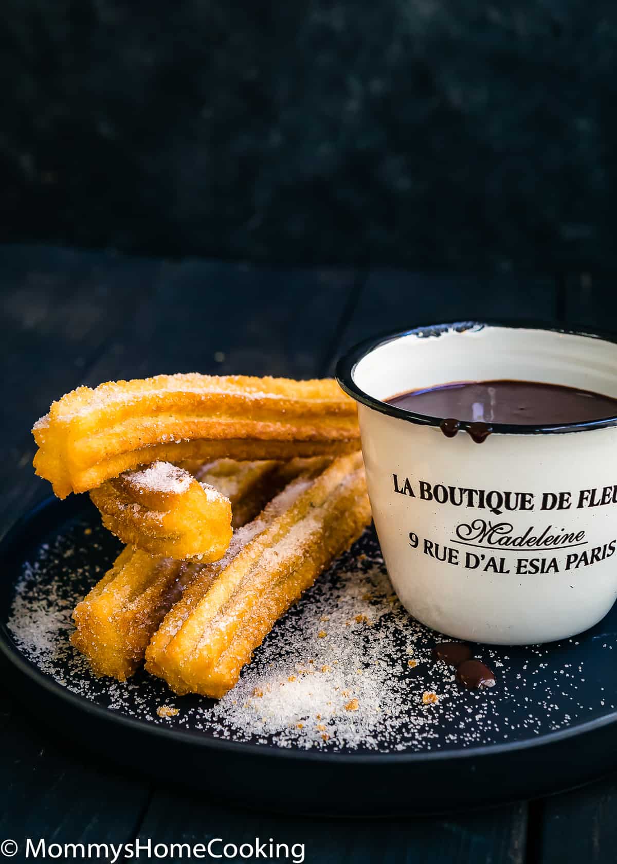 fried homemade churros with chocolate sauce on the side on a plate.