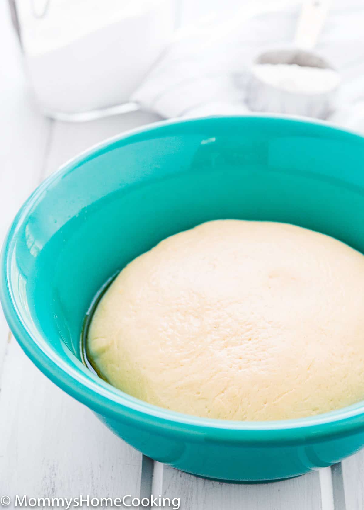 risen homemade pizza dough in a blue bowl