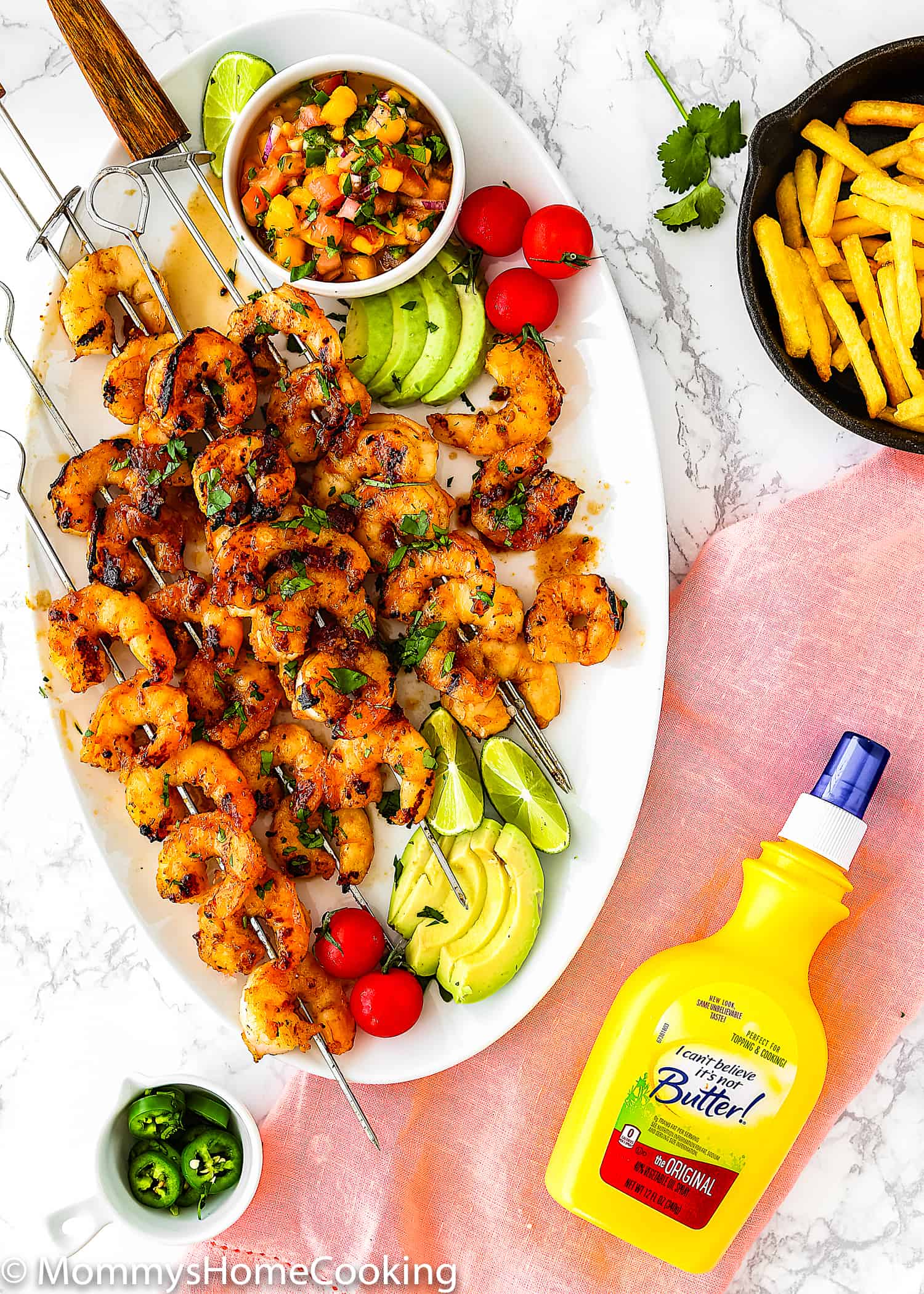 Honey Chipotle Grilled Shrimp in a white oval plate served with sliced avocado, cherry tomatoes, mango salsa and bottle of I Can’t Believe It’s Not Butter! Original Spray 
