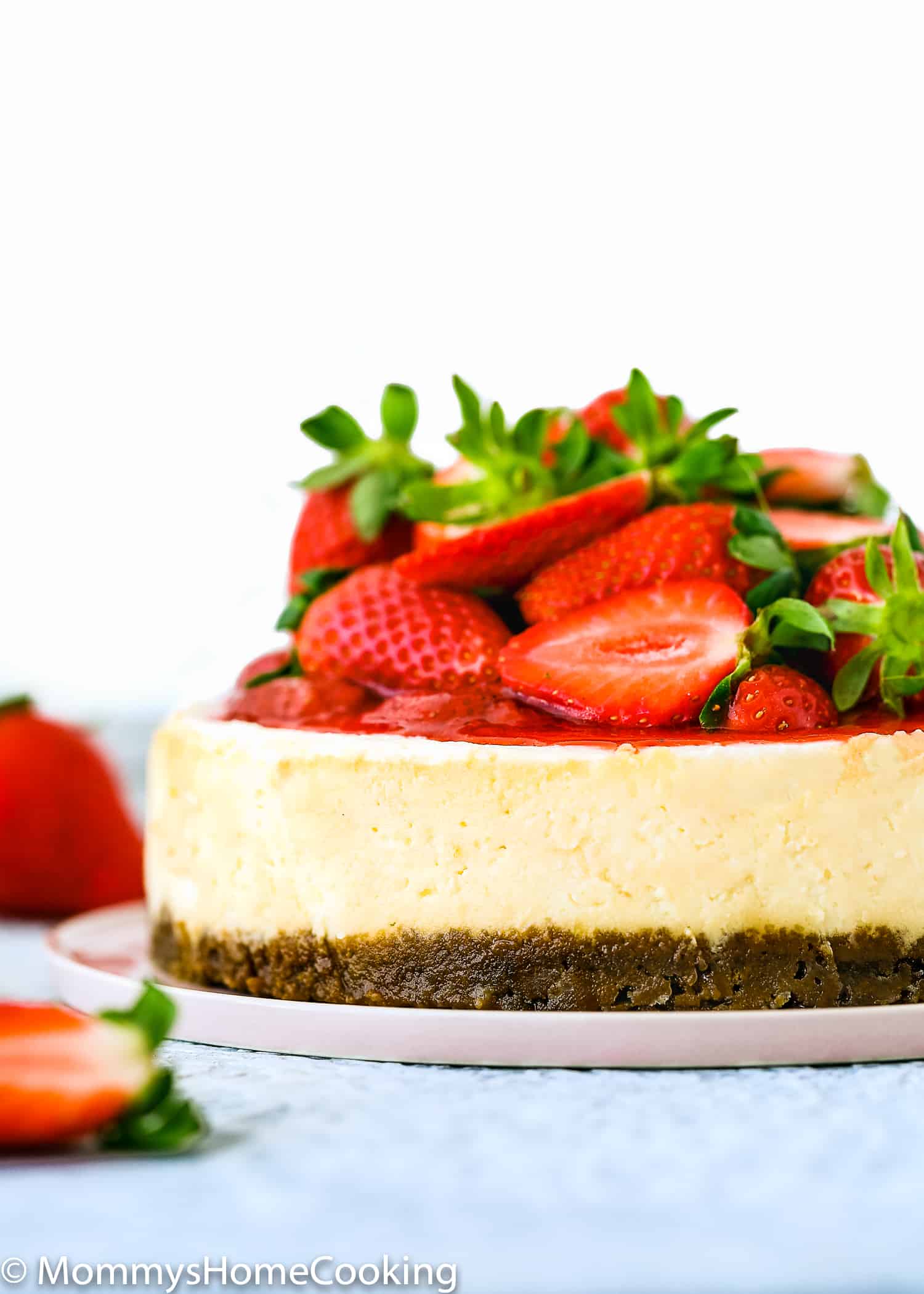 Eggless Cheesecake topped with strawberry sauce/topping and fresh strawberries.