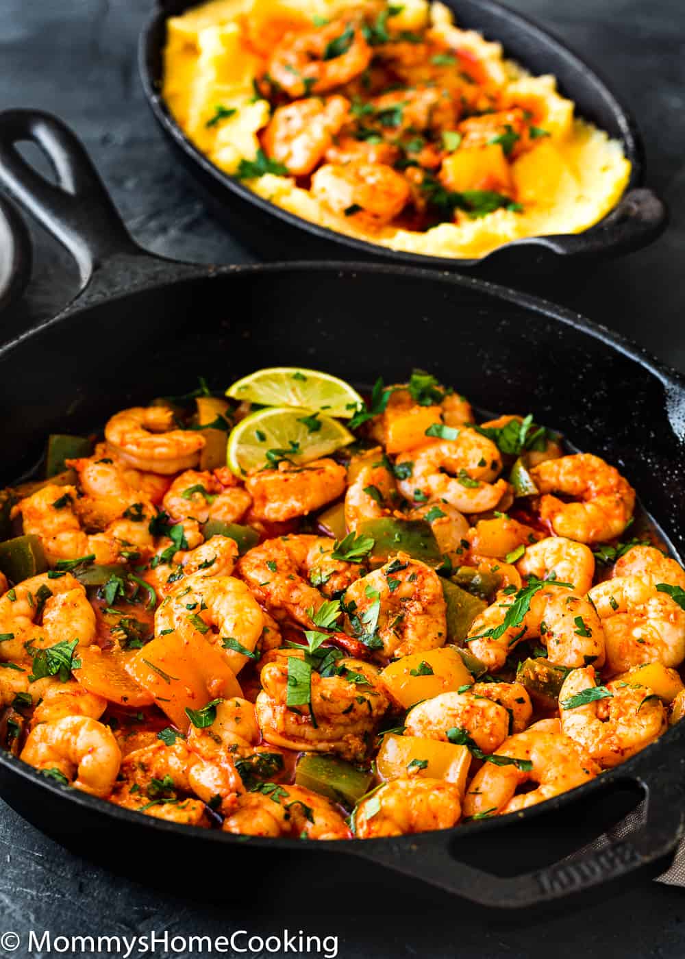 Easy Peri Peri Shrimp in a cast iron skillet garnished with parsley and lemon wedges