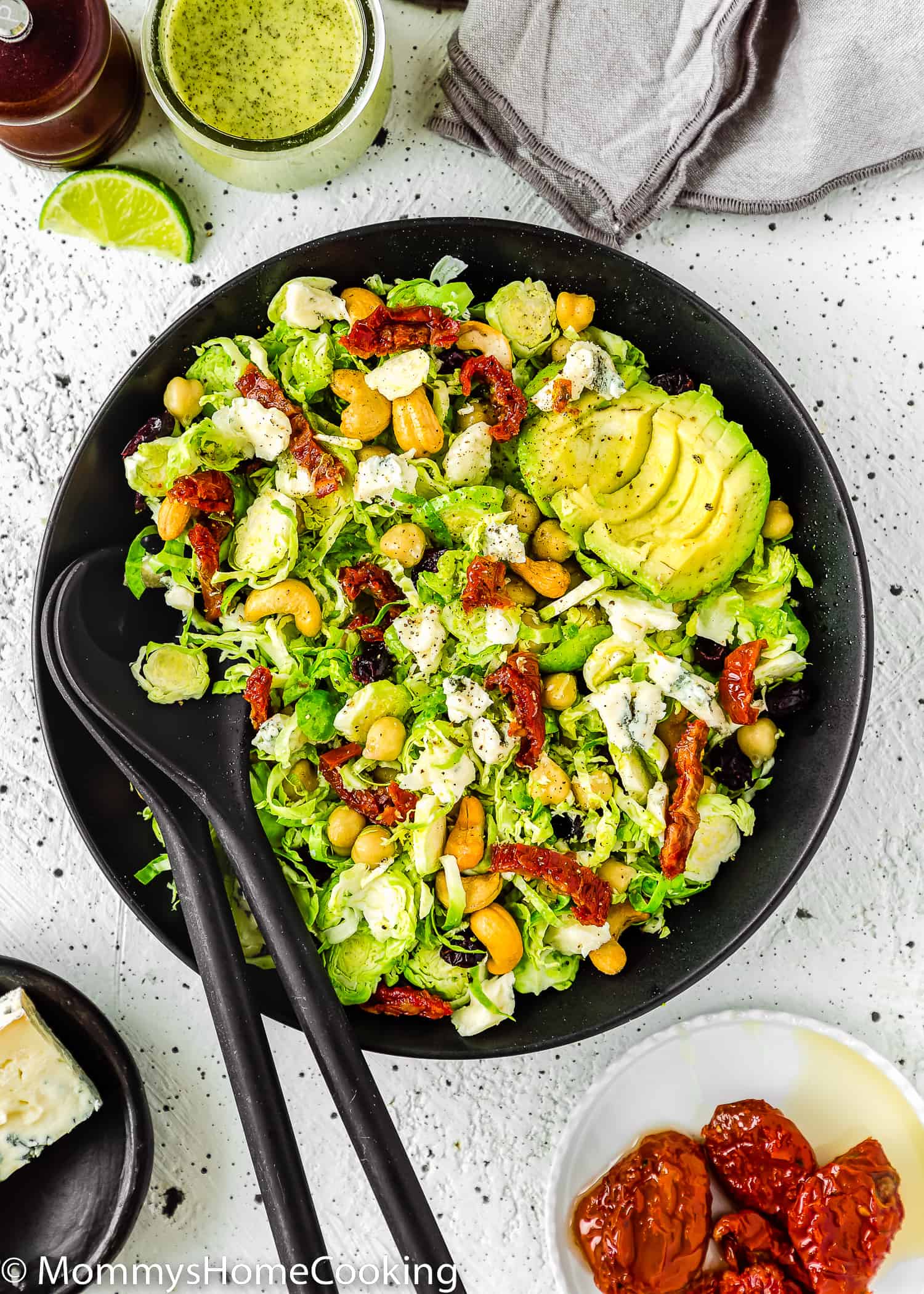 Shaved Brussels Sprout Salad in a salad bowl with serving spoons on the side.