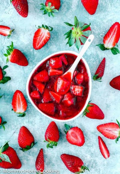 Strawberry sauce/topping in a white bowl and fresh strawberries