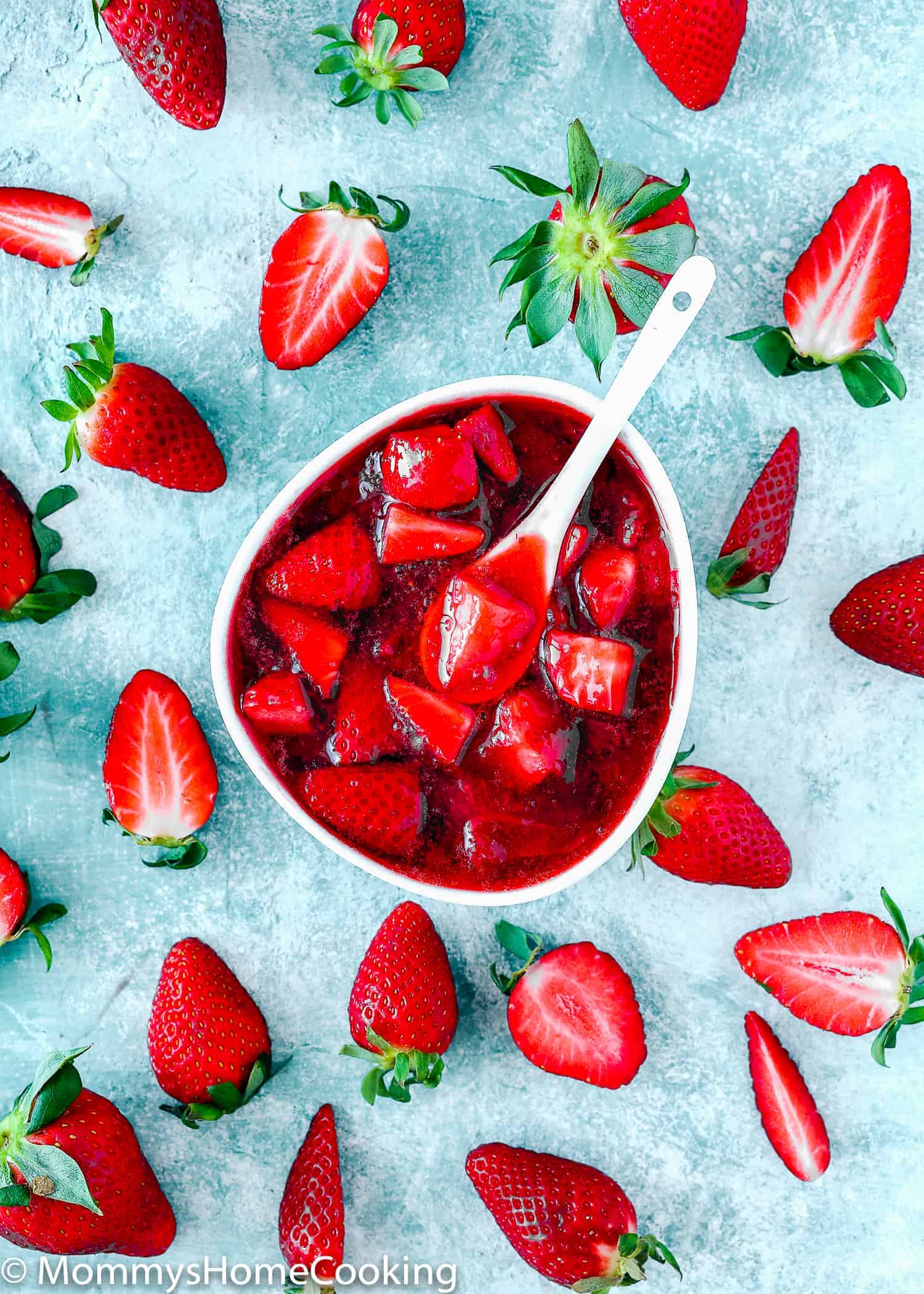 strawberry sauce topping  in a white bowl and fresh strawberries.