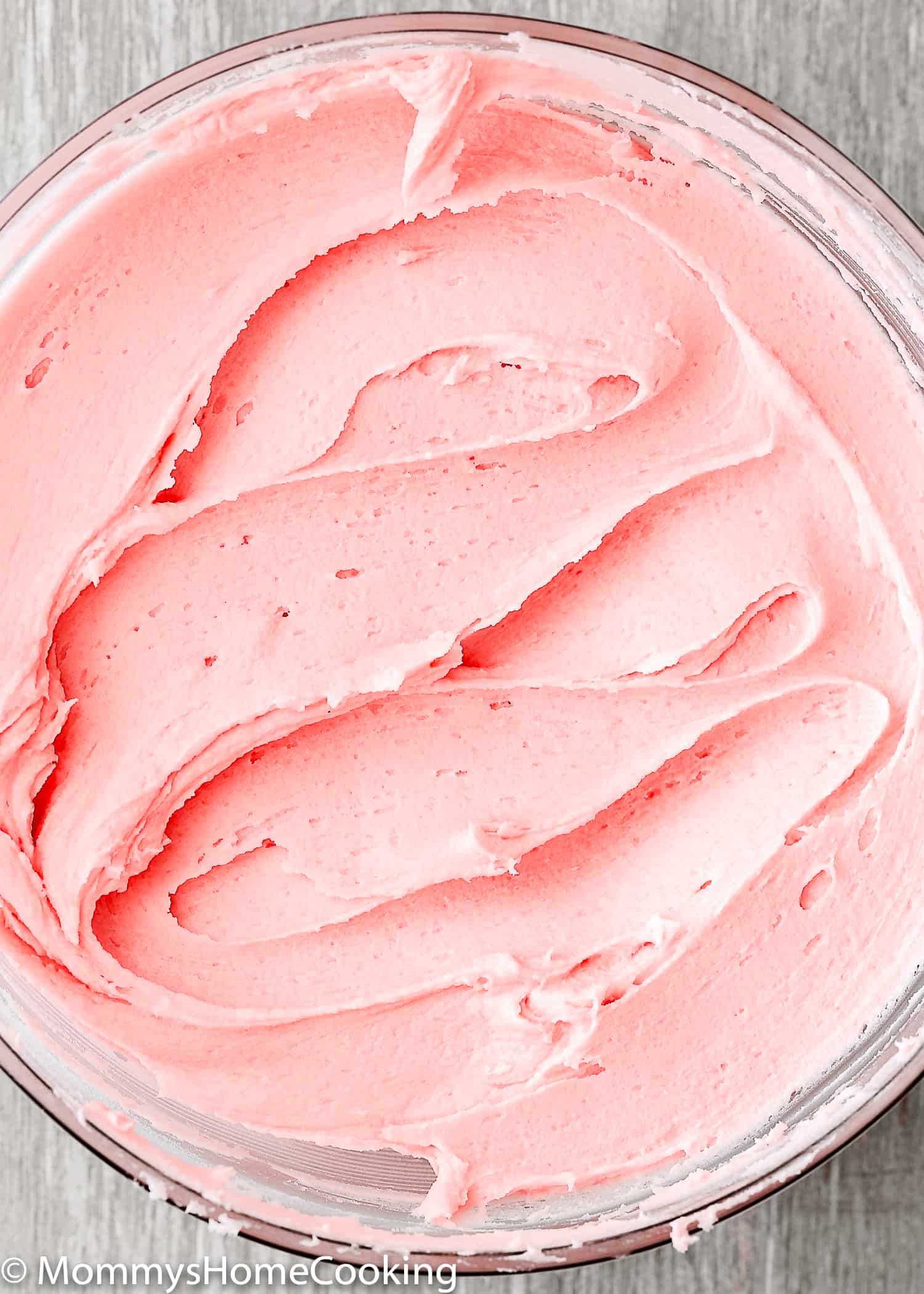 Pink buttercream frosting in a glass bowl