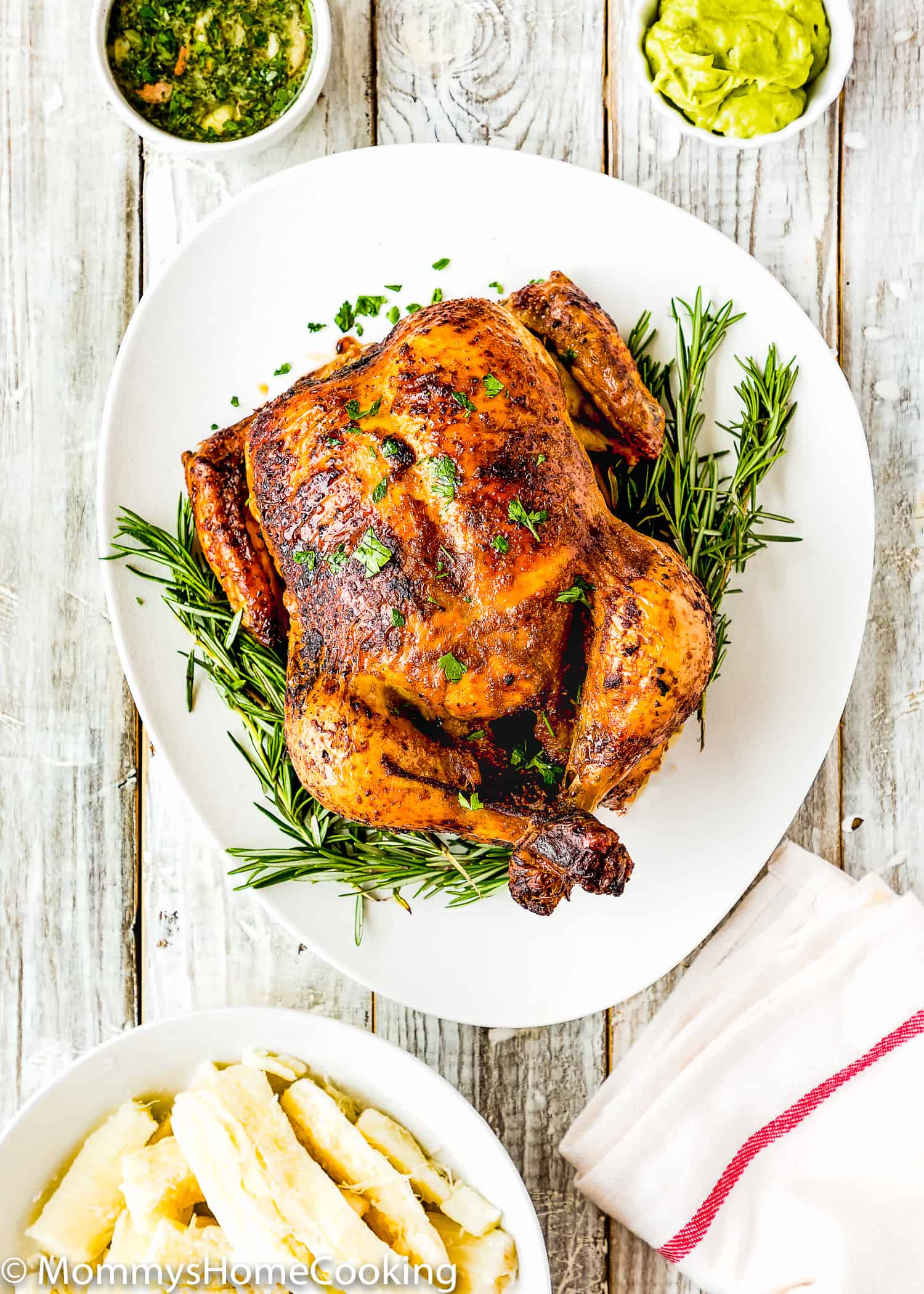 Venezuelan style roasted chicken in a white serving plate with mojo, yuca and guasacaca on the side.