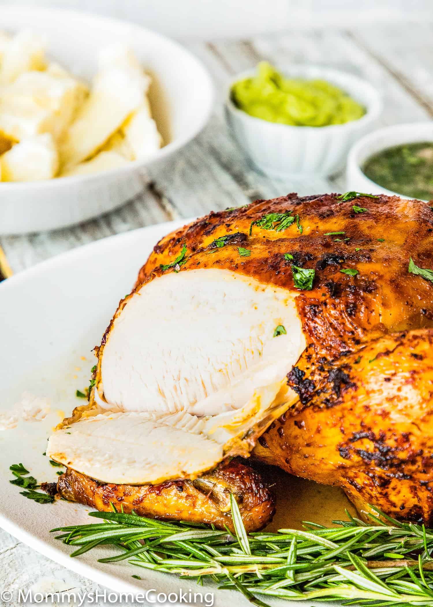 sliced Venezuelan style roasted chicken over a plate with fresh rosemary.