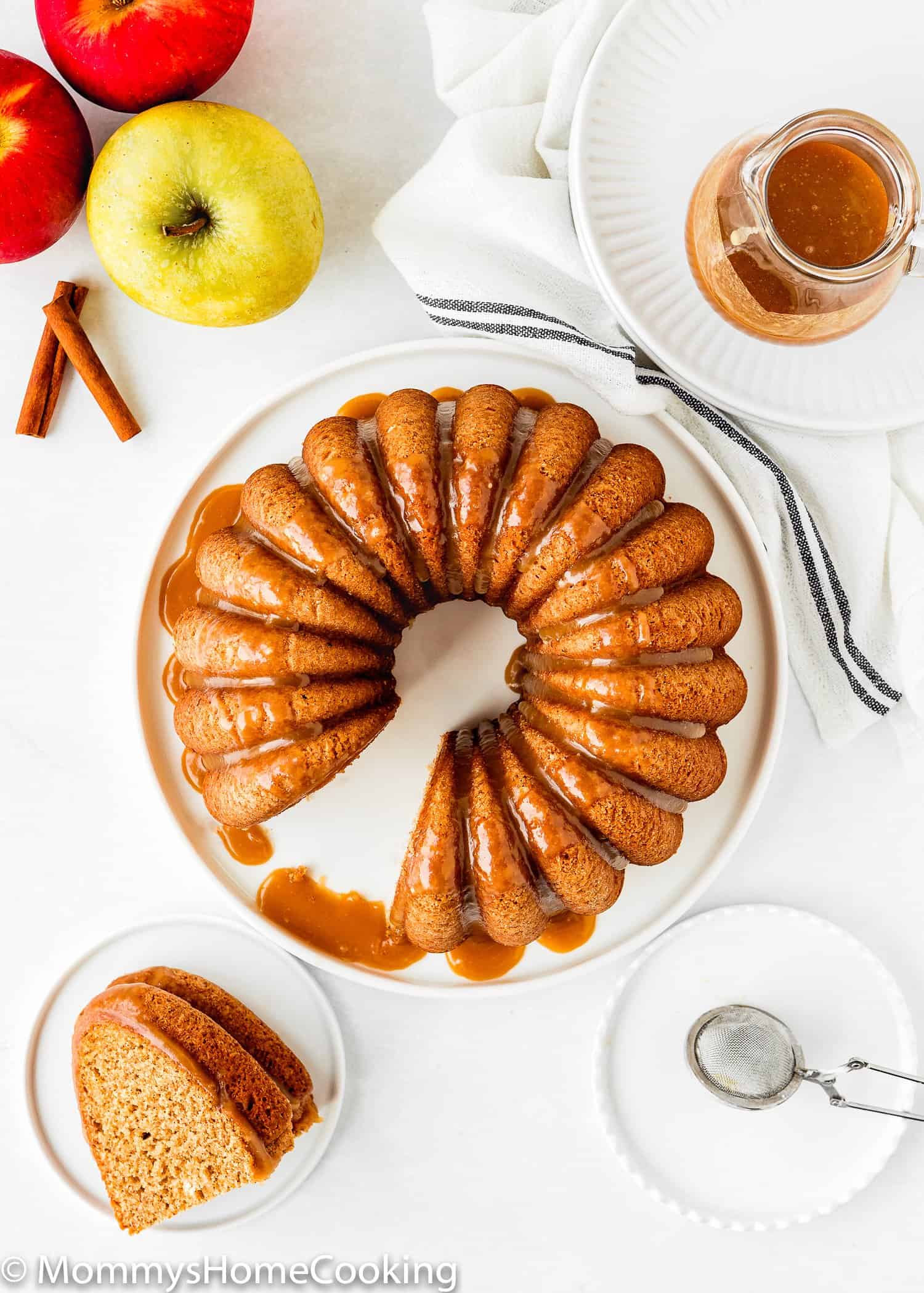 overhead view of a sliced Eggless Apple Cider Donut Cake with brown sugar glaze with apples on the side.