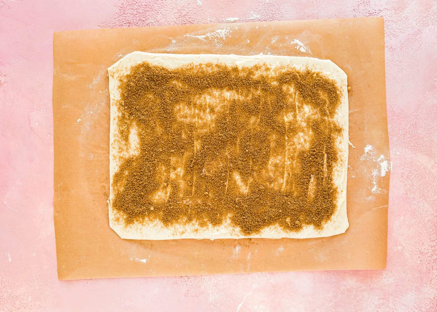 egg-free dough rolled into a rectangle with butter and cinnamon sugar on top over parchment paper. 
