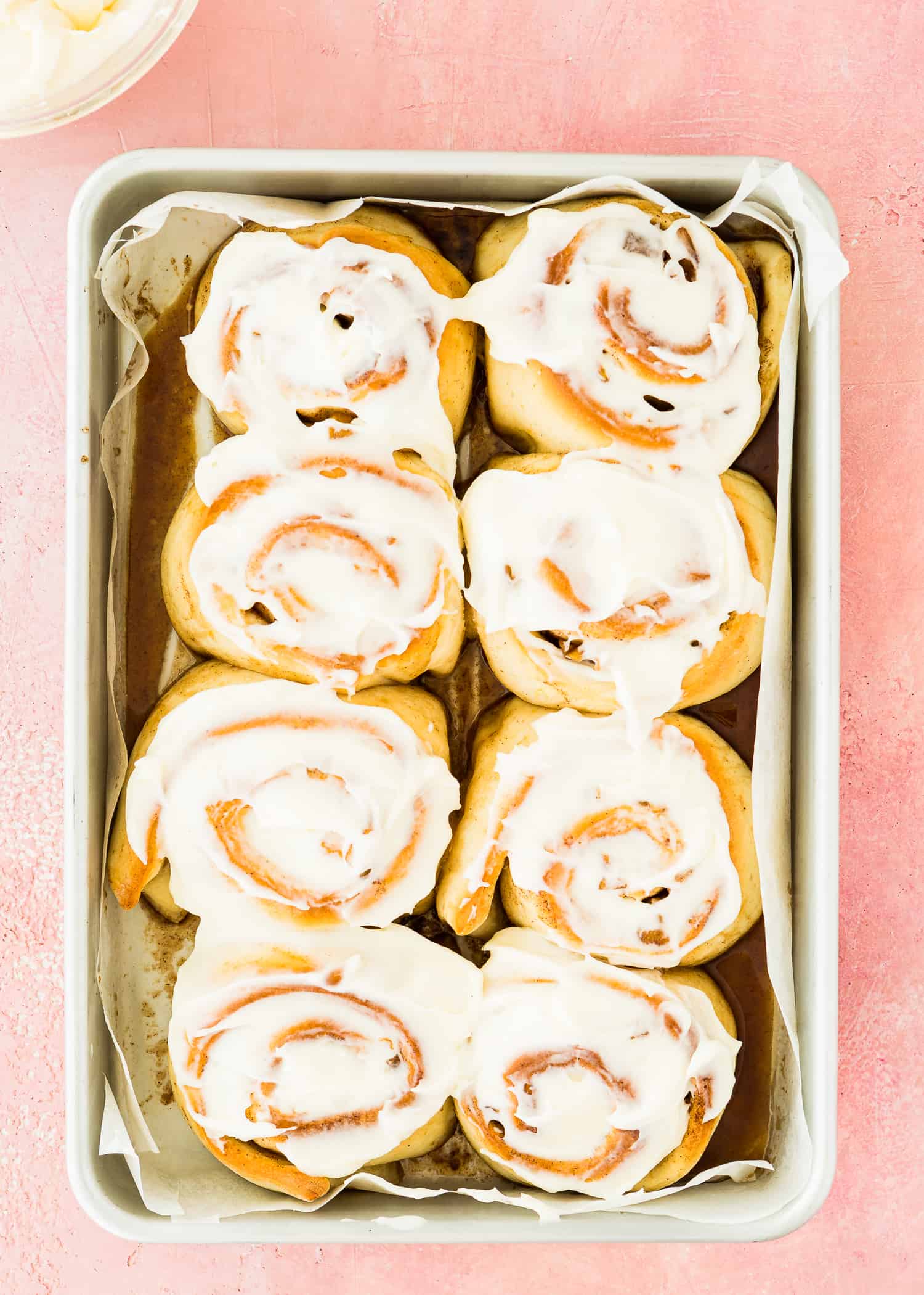 egg-free apple cinnamon rolls in a baking pan with icing on top. 