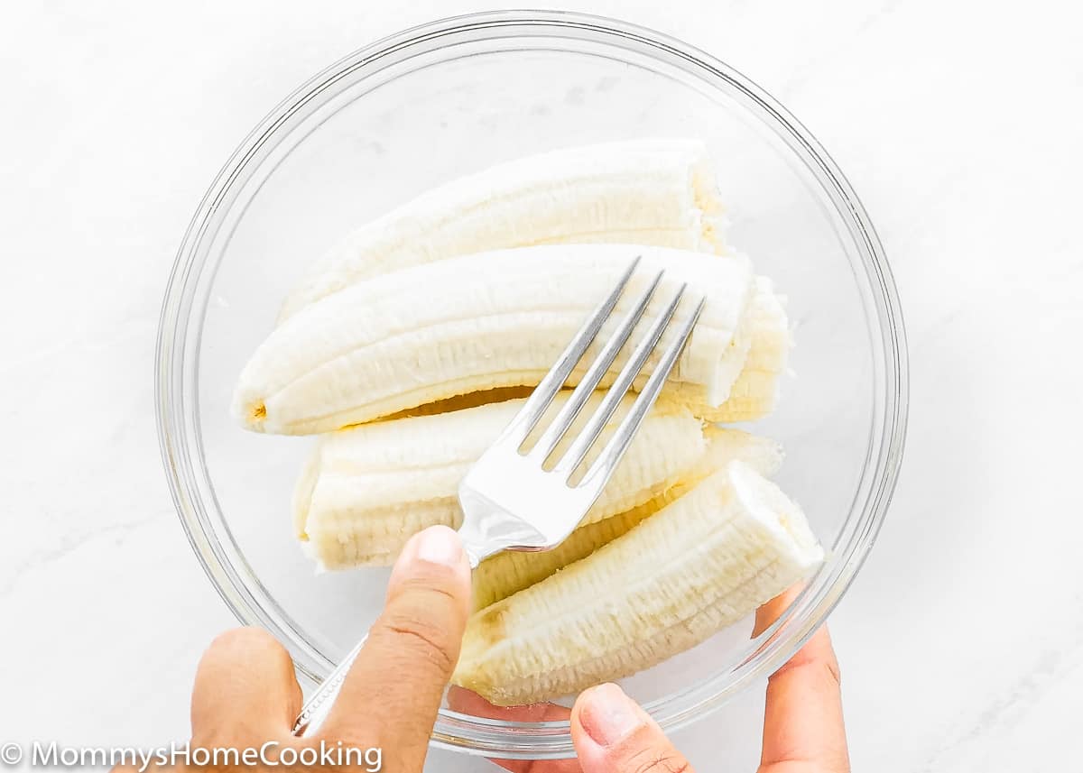 bananas in a bowl being mash with a fork