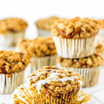 eggless banana crumb muffins with glaze over a white surface