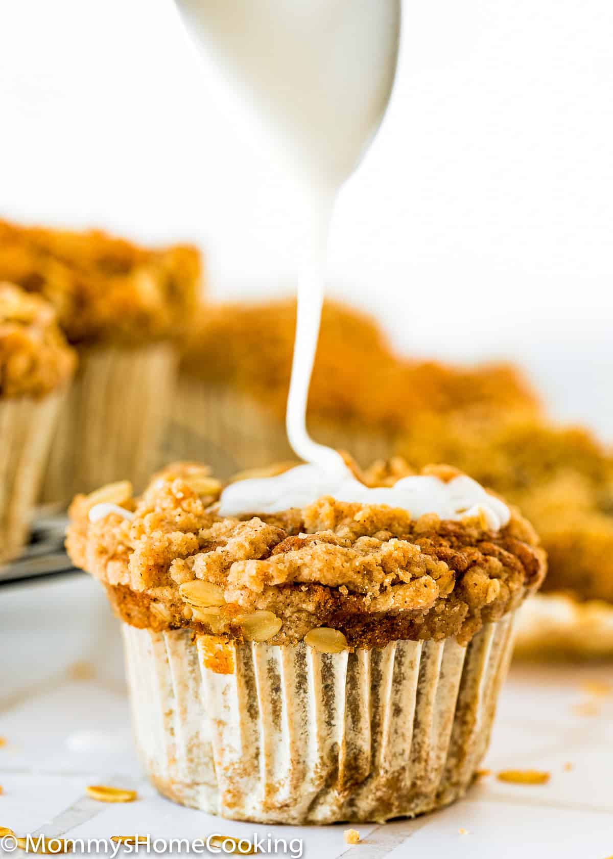 sugar glaze being poured over a egg-free crumb banana muffins.