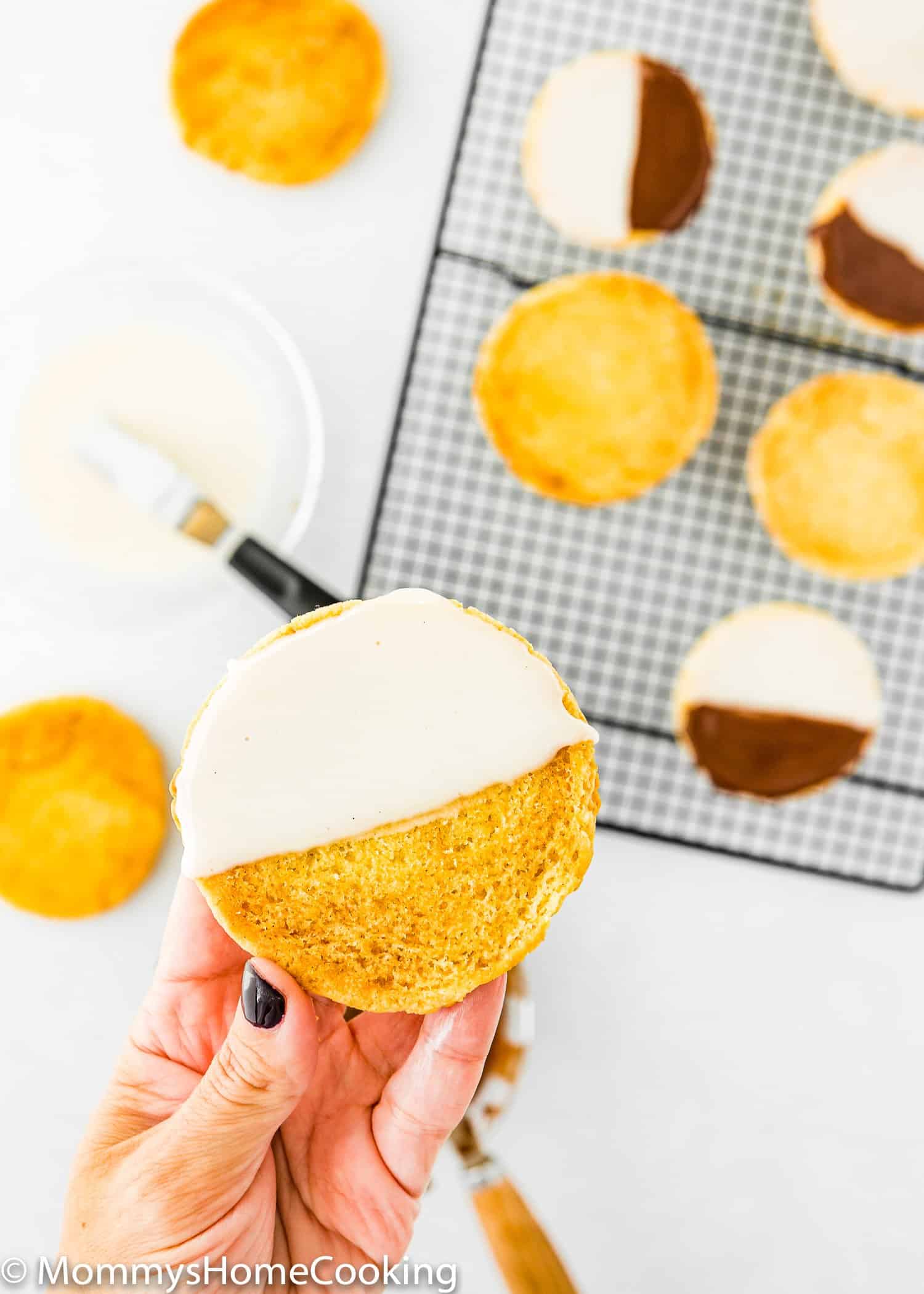 hand holding a egg-free cookie with vanilla frosting