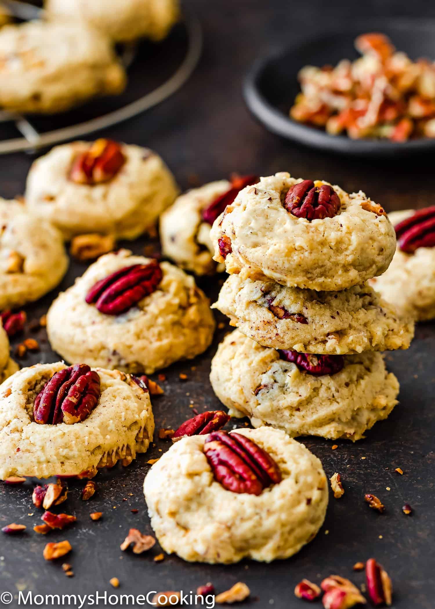 Eggless Butter Pecan Cookies over a slate surface with a little bowl with chopped pecan in the background