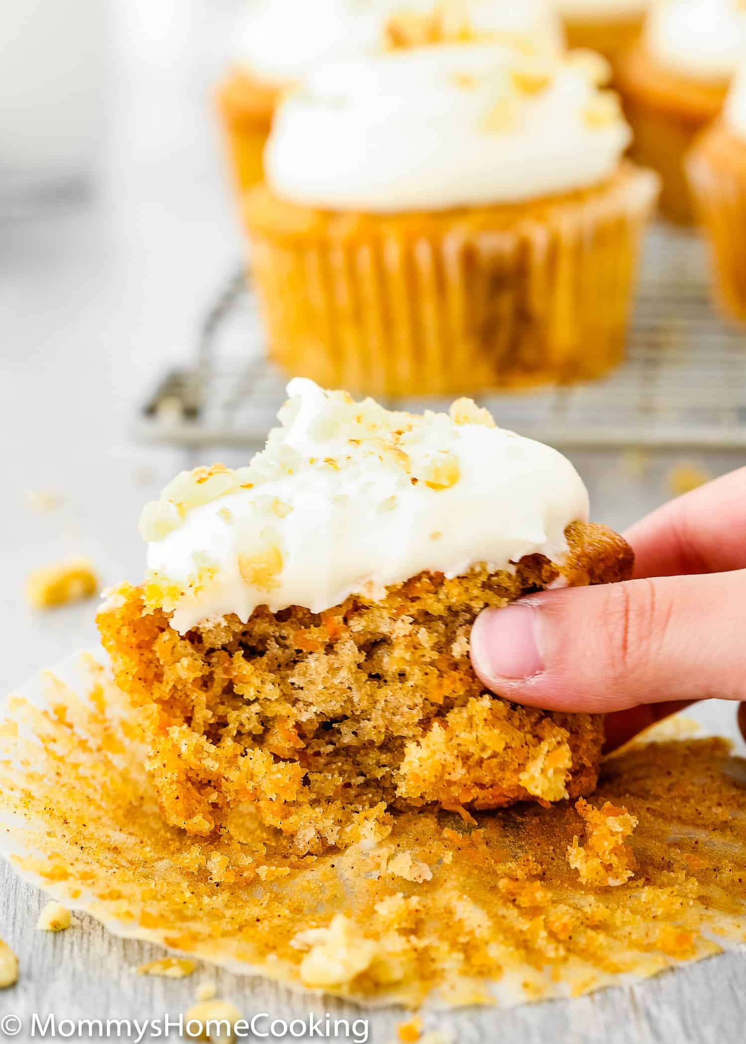 a hand holding an Eggless Carrot Cake Cupcakes cut open showing its fluffy texture. 
