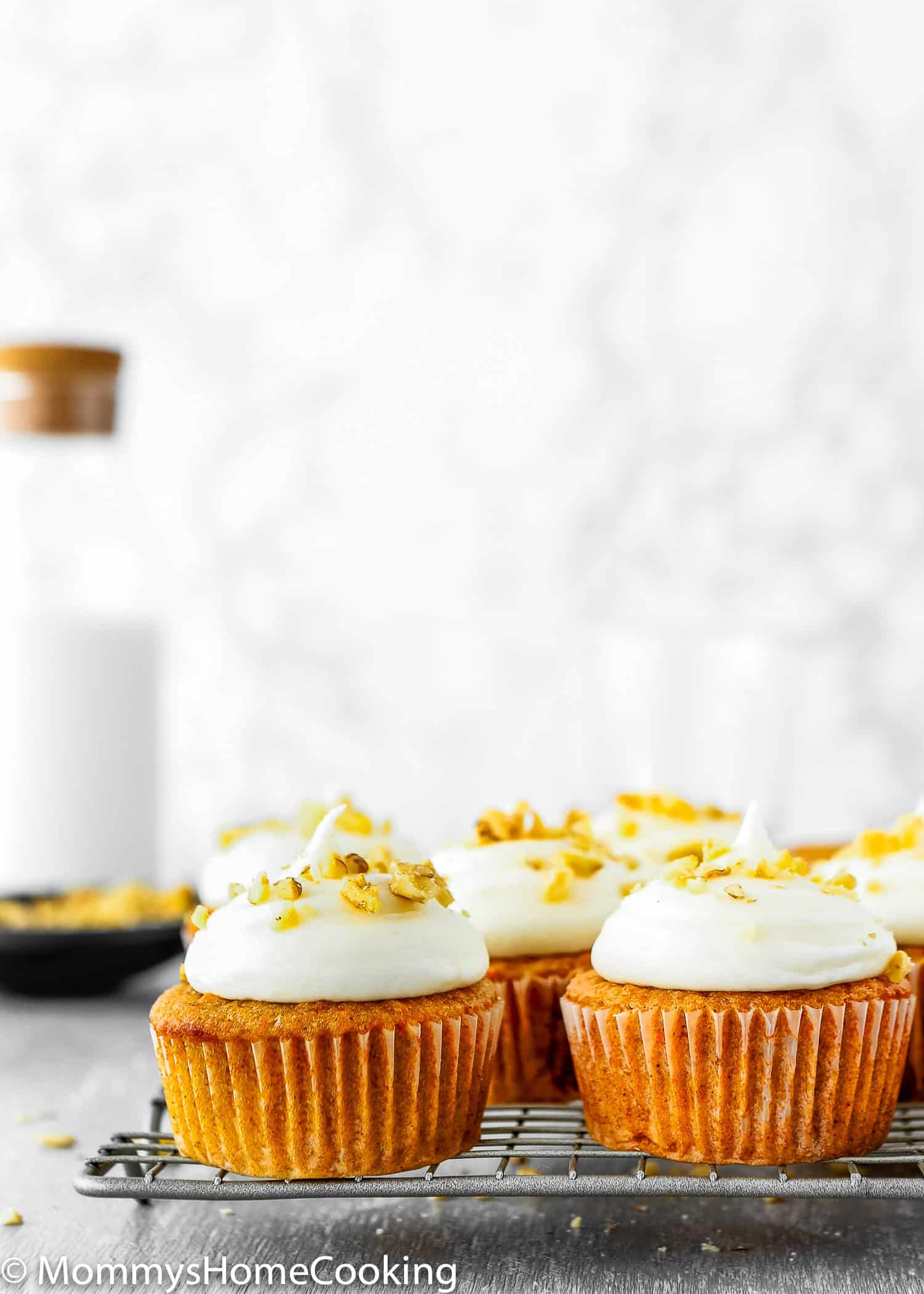 Eggless Carrot Cake Cupcakes with frosting over a cooling rack. 