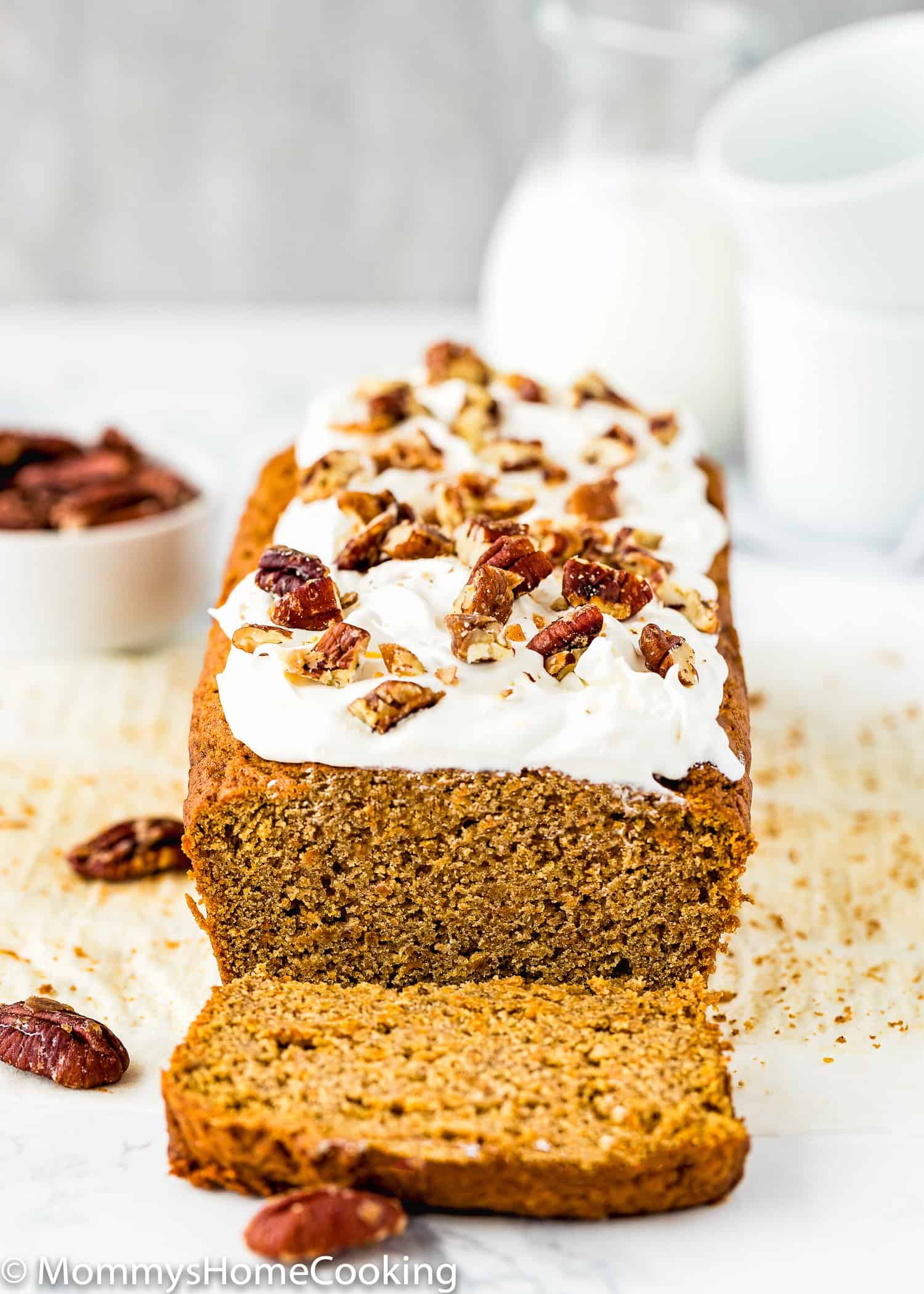 sliced Eggless Carrot Cake quick bread with frosting and chopped pecans.