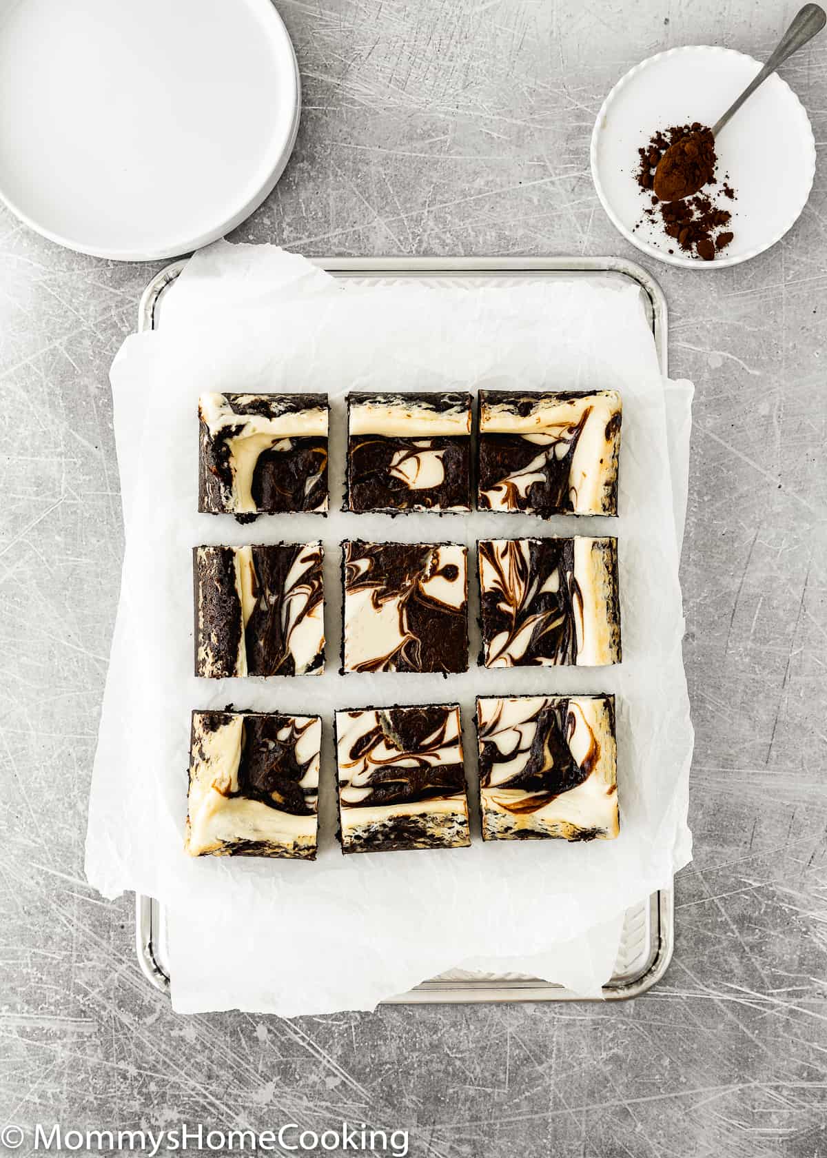 Eggless Cheesecake Brownies squares over a baking tray with parchment paper.