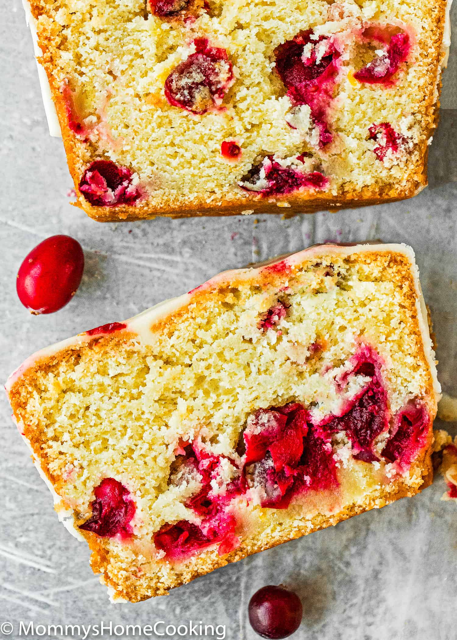 two slices of Eggless Cranberry Orange Bread over a gray surface.