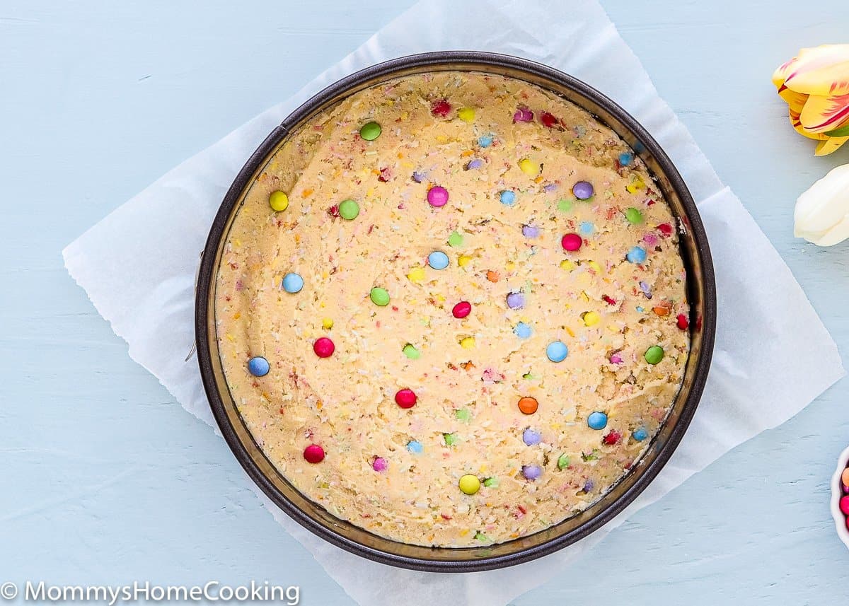 egg free cookie dough into a springform pan with chocolates candies in top
